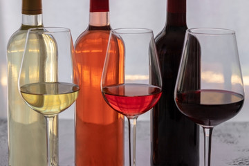 Different wines  bottles red, white and rose awith wi9ne glasses on concrete light background. Wine degustation concept. Copy space