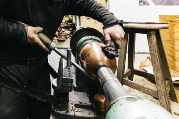 A craftman is making copper hand made cooking pots, saucepan and handicraft, only hands is showing...