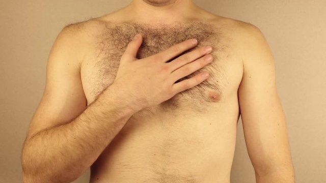a man touches his hairy chest