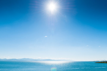 Fototapeta na wymiar Bright sun shines on Lake Sevan on a clear day, a landmark of Armenia