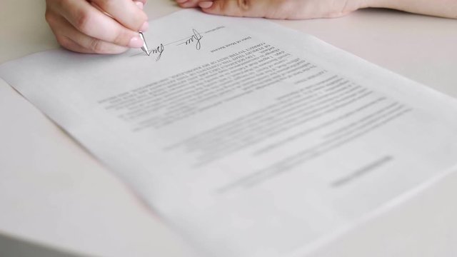 Top view of person heand signs the document. Close-up shot