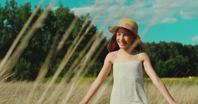 Cheerful preteen girl walking at camera in the field at Sunny Day. Slow motion