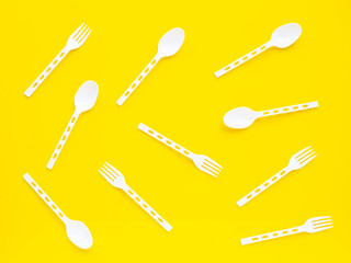 Plastic spoon and fork on yellow background.