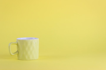 Little yellow porcelain cup isolated on yellow background. Still life concept with copy space. 