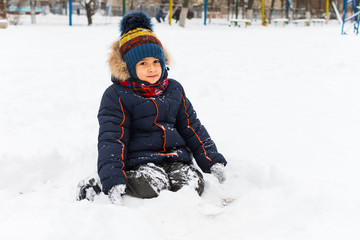 boy 5 years old playing with snow outdoors in winter