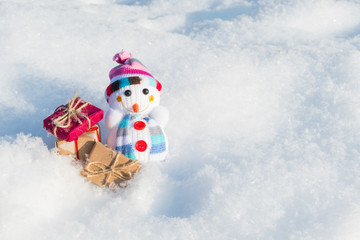 funny toy snowman with gifts in a snowdrift with a copy of space
