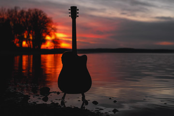 Guitar by the lake at sunset time.