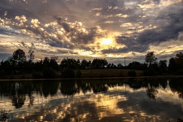 Incredible sunset view over a serene country pond with a canoe in foreground
