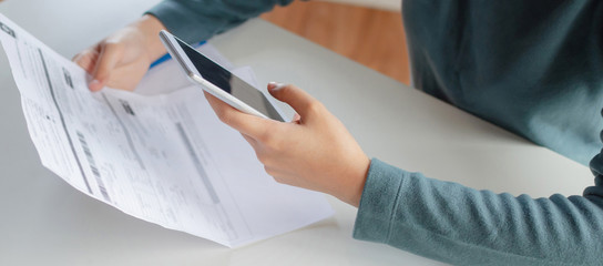 panoramic banner. hand of young woman using calculator for calculating family budget cost bills on...