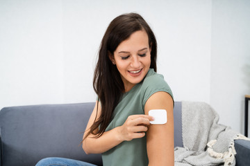 Woman Applying Patch On Her Arm
