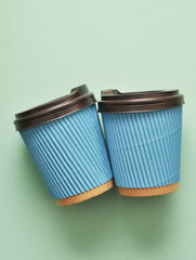 Blue paper coffee cups on mint color background.