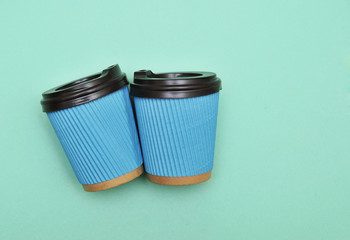 Blue paper coffee cups on mint color background.