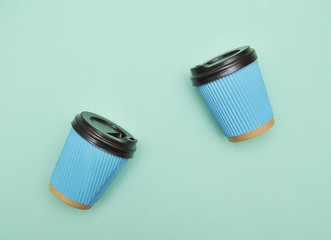 Blue paper coffee cups on mint color background.