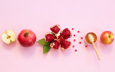 Concept Rosh Hashanah postcard with copy space ; apples, pomegranates and honey on pink background