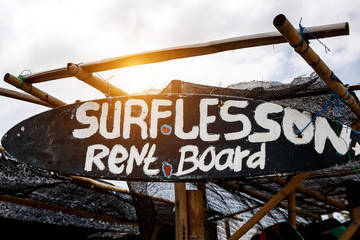 The inscription "Surf lesson" on black surfboard. Advertising on the beach.