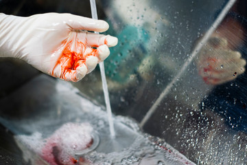 hands with bloody latex gloves washing
