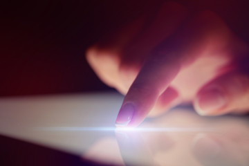 Finger touching tablet with dark background with copyspace