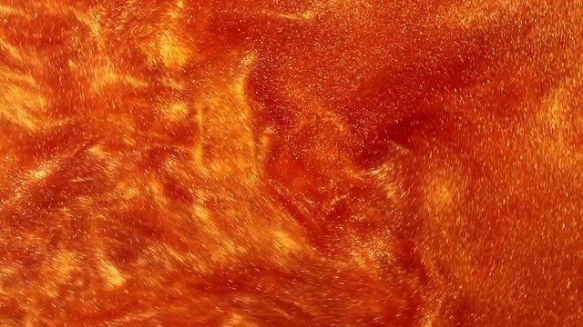 orange liquid with dye and sparkles. abstract moving background