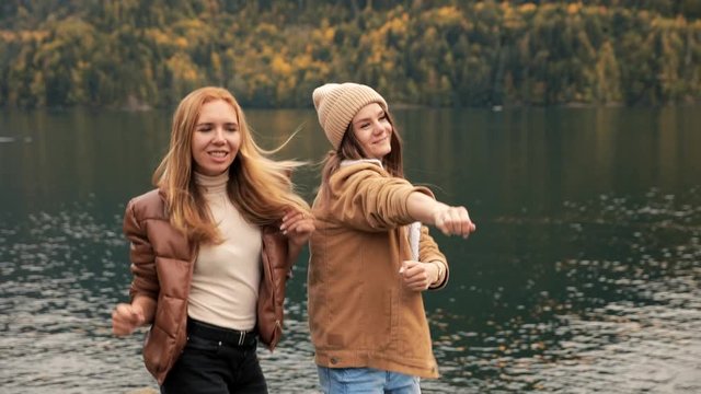 FAIL of two girls on the lake on the background of mountains dance for a blog and laugh. Social media travel vlog enjoying vacation travel adventure