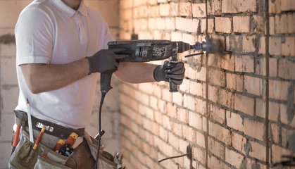 Handyman uses jackhammer, for installation, professional worker on the construction site. The...