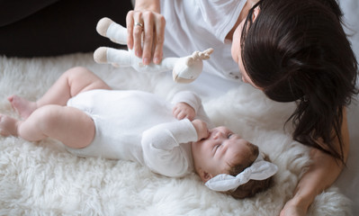 Obraz na płótnie Canvas Mom plays with a toy with her newborn daughter.