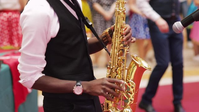 Musician playing saxophone on city sidewalk closeup
