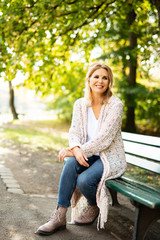 Attraktive Frau im mittleren Alter sitzt im Park auf einer Bank