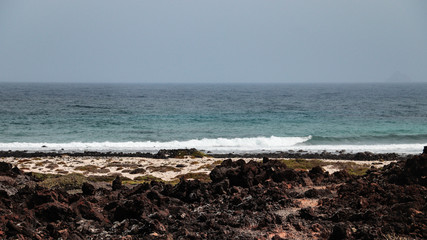 Exotic white sand beach with volcanic rocks on the foreground