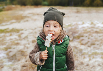 Little girl eating roasted marshmallow by a self-made campfire. Fun family time concept.