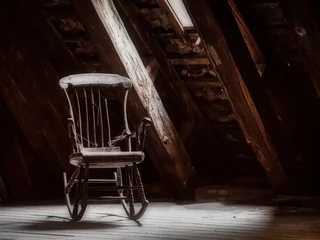 Fototapeten Old wooden rocking chair on a attic with a light beam through a window © LauraFokkema