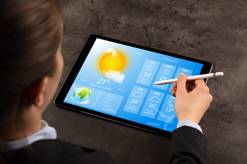 Business woman checking weekly weather forecast on tablet