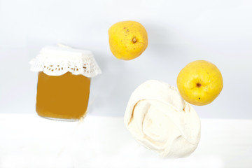 Jar of quince jam. Soars in the air. Quince fruits and marshmallows in the form of a rose soar nearby.