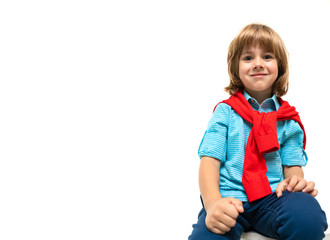 Little caucasian boy sits on a chair with red sweatshot around his neck isolated on white background
