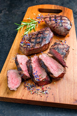 Traditional barbecue dry aged sliced wagyu sirloin beef steak with spice and herbs as closeup on modern design wooden cutting board