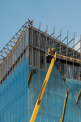 cranes on glass facade office building under construction -