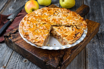 Traditional apple jalousie cake offered as closeup in a backing form on an old rustic wooden board