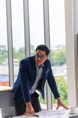 A young Asian businessman wears glasses to touch his desk in a comfortable