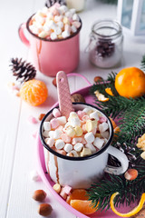 Cups of hot chocolate with marshmallows, mandarin, fir tree branches and nuts on white wooden background