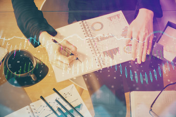 Double exposure of hands making notes with forex chart huds. Stock market concept.