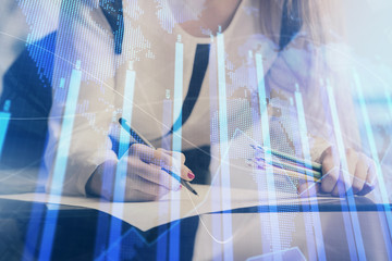 Double exposure of hands making notes with forex chart huds. Stock market concept.