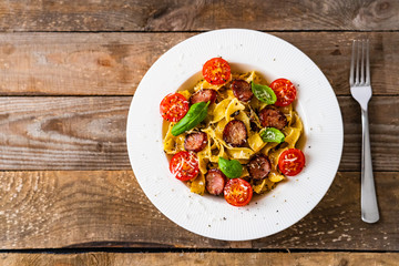 Tagliatelle with sausages on wooden table