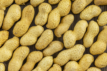 Background of unpeeled peanuts on a dark surface, top view