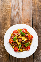 Tagliatelle with sausages on wooden table