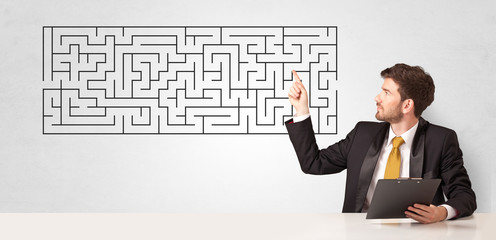 Businessman presenting a maze on a wall