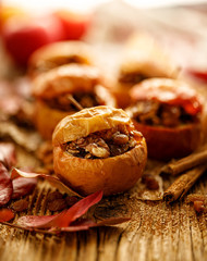 Baked apples stuffed with nuts, raisins and seeds with honey and cinnamon on a wooden table, close-up. Delicious fruit dessert.