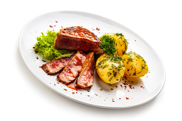 Grilled steak, boiled potatoes and vegetable salad on white background