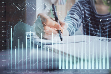 Financial forex graph drawn over hands taking notes background. Concept of research. Double exposure