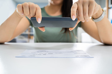 Woman Taking Photo Of Cheque To Make Remote Deposit