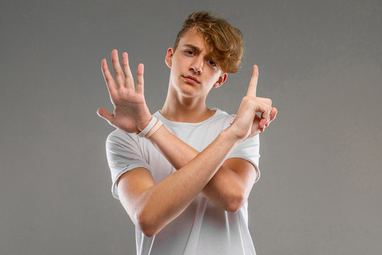 A portrait of young caucasian man with short red curly hair in white t-shirt show a six fingers isolated on a grey background