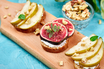 Antipasto. Italian food.  Bruschetta and Crostini with pear, ricotta cheese, honey, figs, nuts and herbs. Breakfast toasts or snack sandwiches. Top view. Copy space.